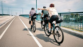 Group of three bikepackers riding over a bridge