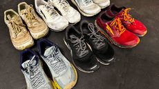 Six pairs of running shoes in two rows of three on a black floor