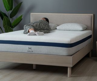 A woman lying on the Helix Midnight Hybrid Mattress.