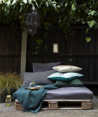 pallet sofa with blueu and grey outdoor cushions and a hanging lantern