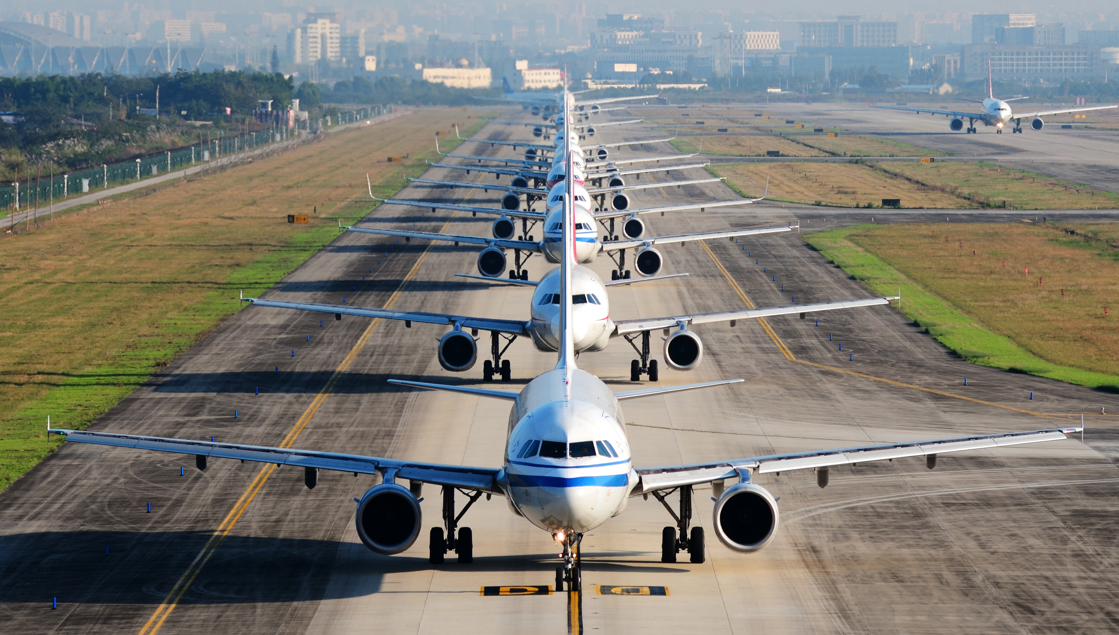 A row of airplanes taxiing on an airport runway.
