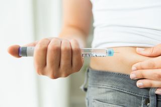 Woman giving herself injection with an insulin pen.