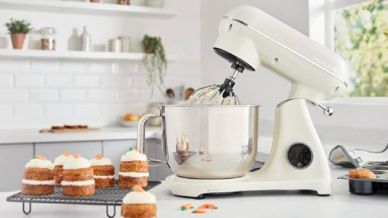 A cream, Lakeland stand mixer in a modern, white kitchen, with mini carrot cake muffins.