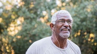 Senior man listens to music through headphones as he goes for a walk