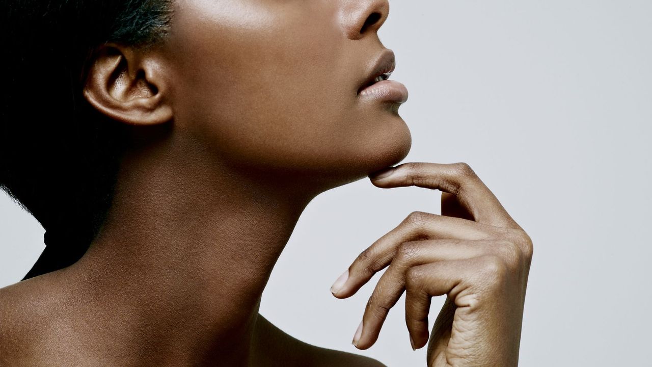 A woman with smooth skin resting her chin on her hand