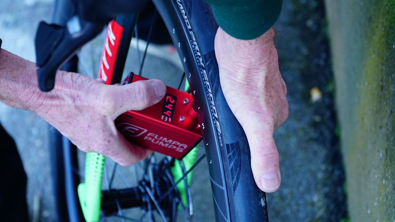 A person inflating bike tyres with a handheld Fumpa Pump