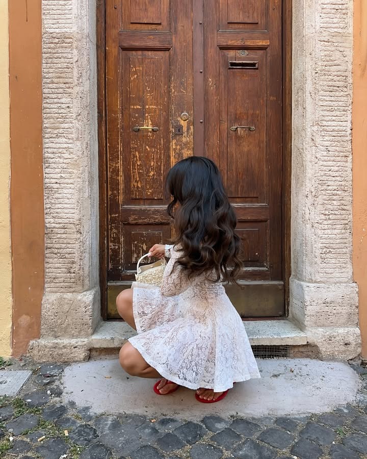 A woman crouching down with long, curled brown hair.