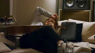 Lewis Capaldi lying on a sofa with a guitar in Lewis Capaldi: How I'm Feeling Now