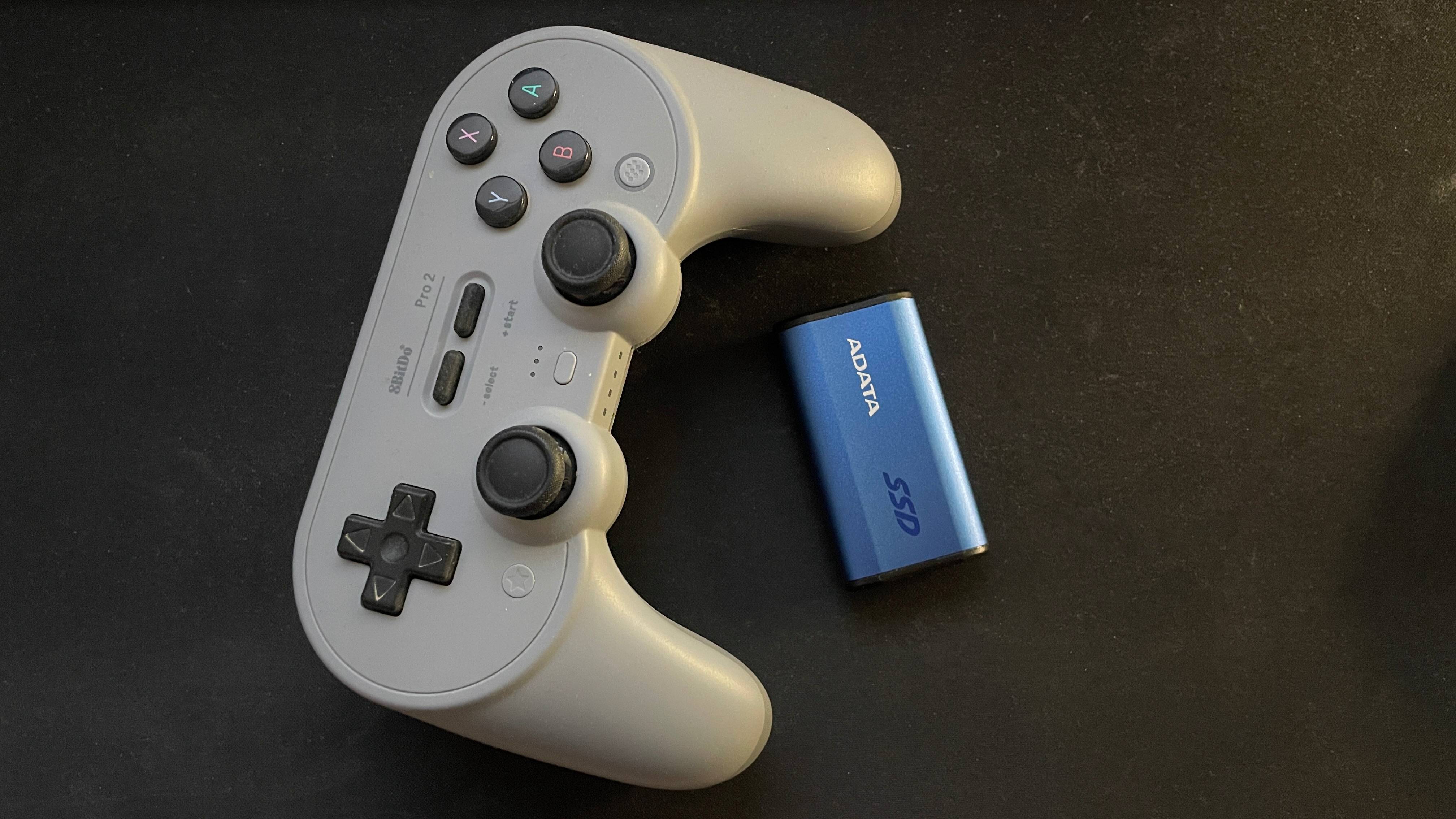 Adata SE880 external SSD next to an 8BitDo Pro 2 controller for size comparison