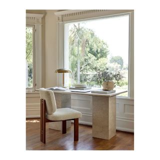marble desk with white boucle chair in front of window