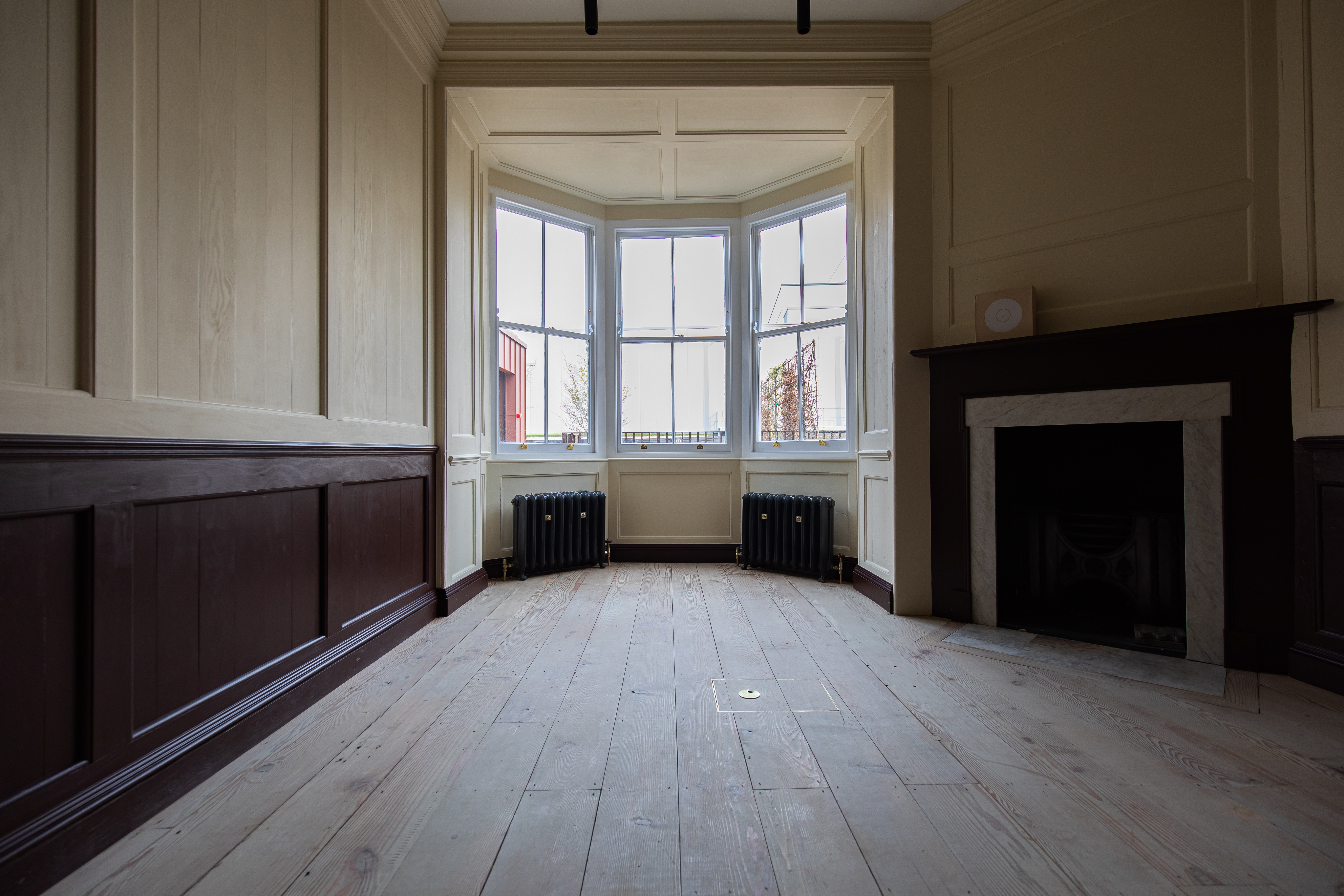 Bare interior with bay window and stripped floorboards at Sarabande Foundation's Tottenham studios