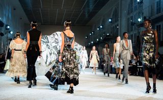 Models wear white dress with puffy sleeves, black top and trousers, black and white patterned maxi dress, and black and white patterned midi dress