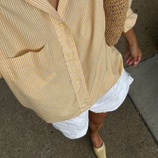 woman wearing white linen shorts and yellow striped button down shirt