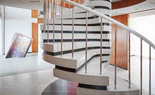 Black and white staircase with chrome railings in a wood-panels hallway with brightly coloured art work