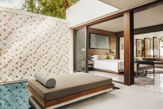 Bedroom with bed in and double doors opening to private pool and sun lounger