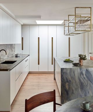 White kitchen with turquoise marble kitchen island and hardwood floors