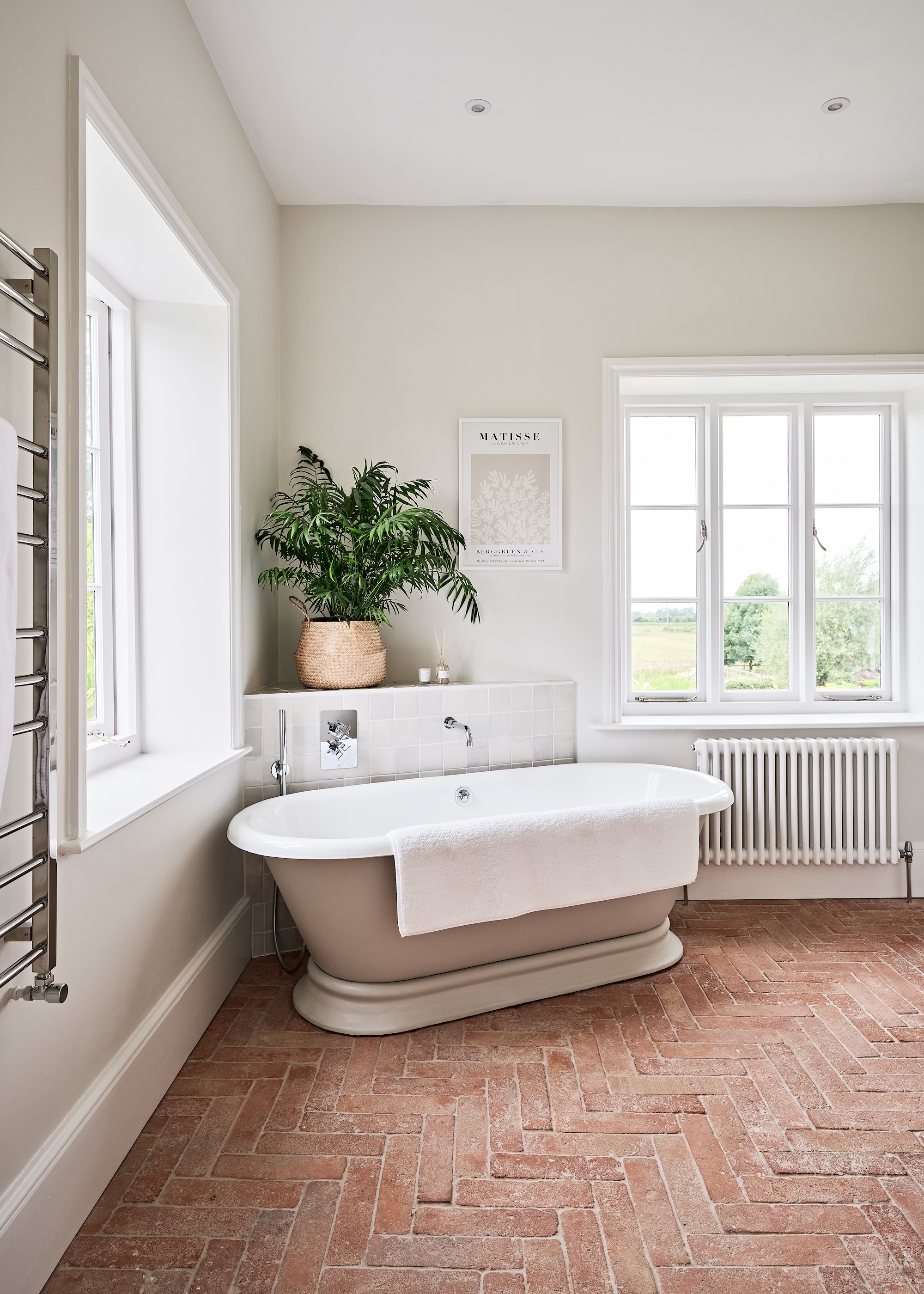 A bath tub on the corner of the room with a large plant above the tub