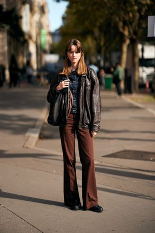 woman wearing black top, leather jacket, and suede pants