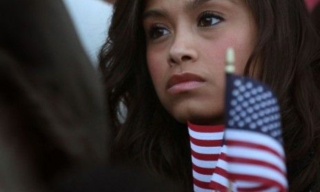 A young woman protesting the Arizona bill holds photos of a family separated by deportation officers.