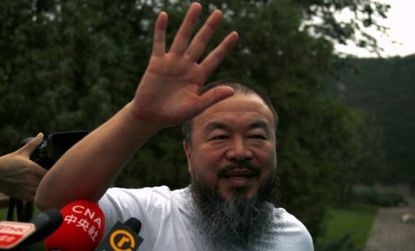 Dissident Chinese artist Ai Weiwei waves from his studio after unexpectedly being released on bail Wednesday.