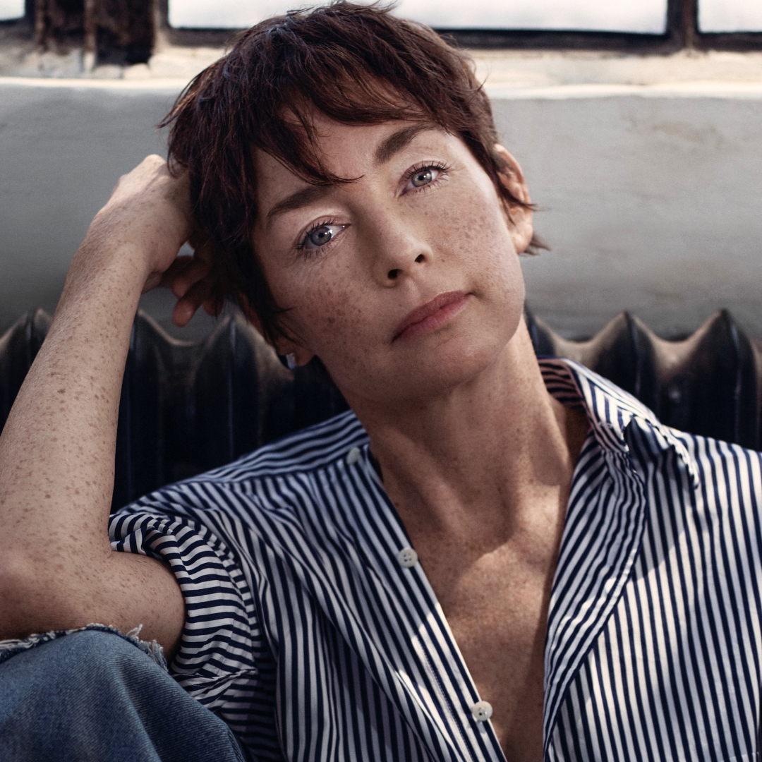 A portrait of actress Julianne Nicholson, sitting in front of a window and a radiator.
