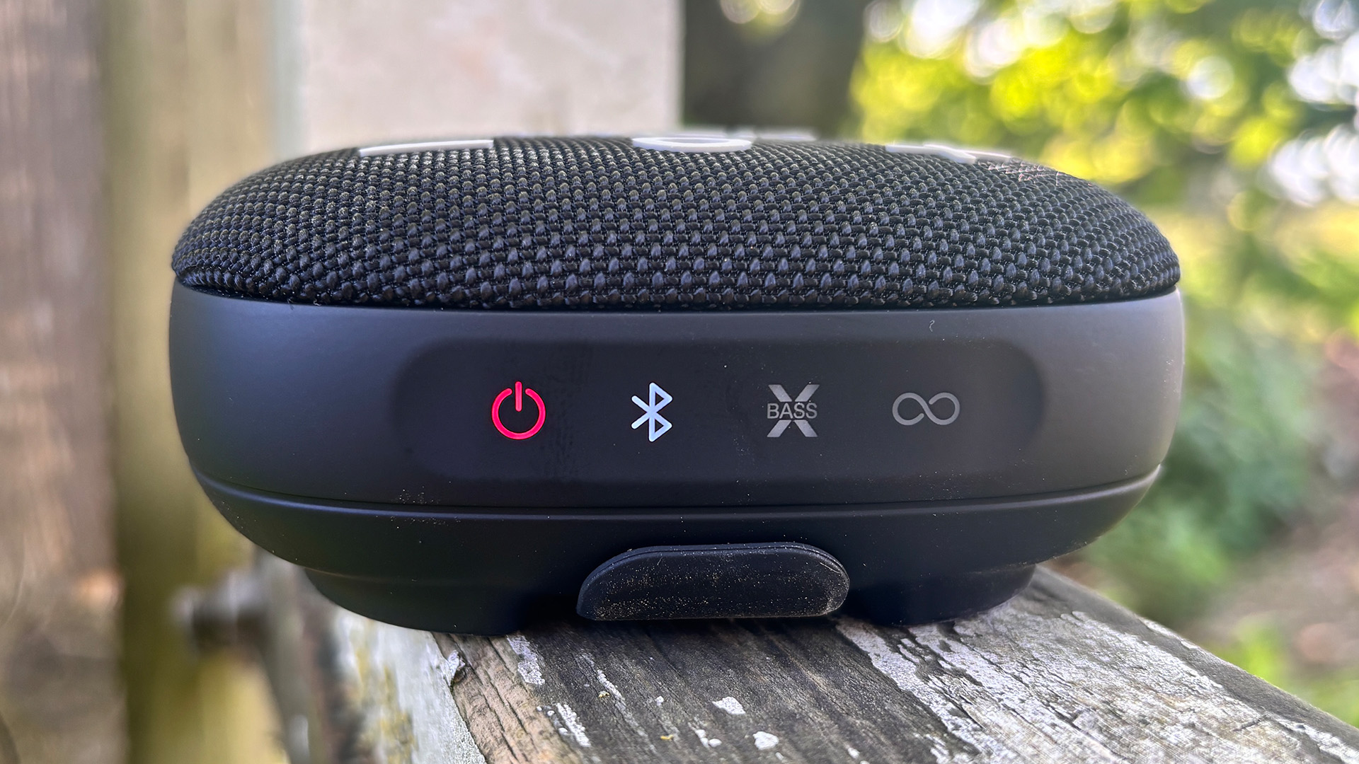 Tribit Stormbox Micro 3 Bluetooth speaker on wooden outdoor surface showing lit-up controls
