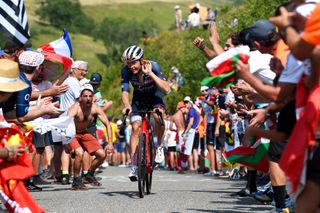 Tom Skujins cups his ear as crowds cheer on the climb of the Peyragudes at the 2022 Tour de France