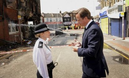 British Prime Minister David Cameron speaks with an officer in south London: Riots that began on Saturday are still raging across the city.