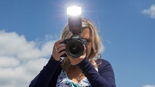 Woman holding Canon EOS 7D DSLR with flashgun