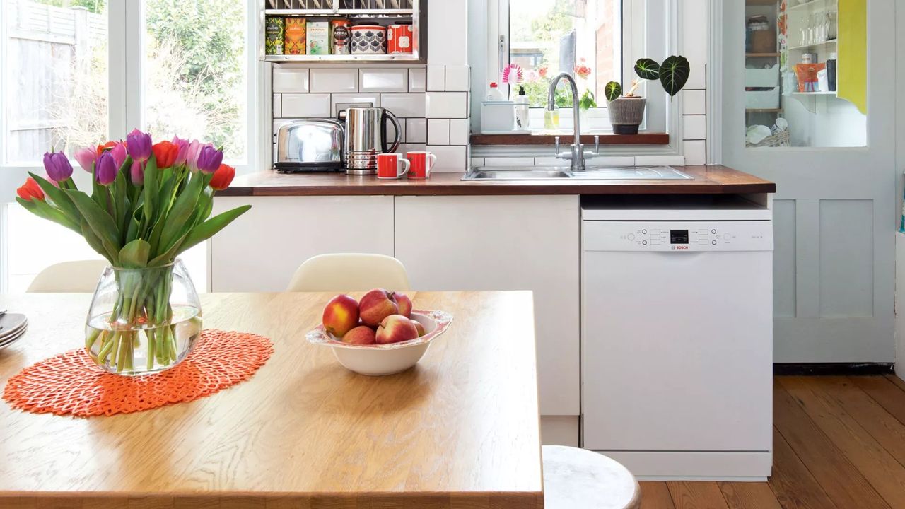 neutral kitchen with wooden table, orange ceiling light and dishwasher