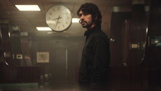 Ben Whishaw standing in a bar looking forward with a straight face.