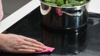 Woman cleaning induction cooktop with a microfiber cloth