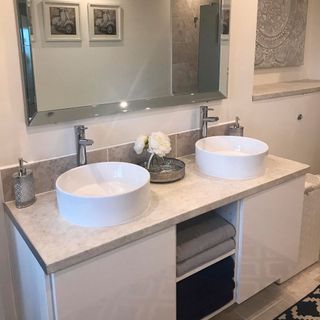 bathroom with wash basin and cabinet with mirror on white walls faucet and white cabinet with bathroom towels