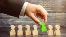 Representation of recruitment, man selecting green figure from wooden options