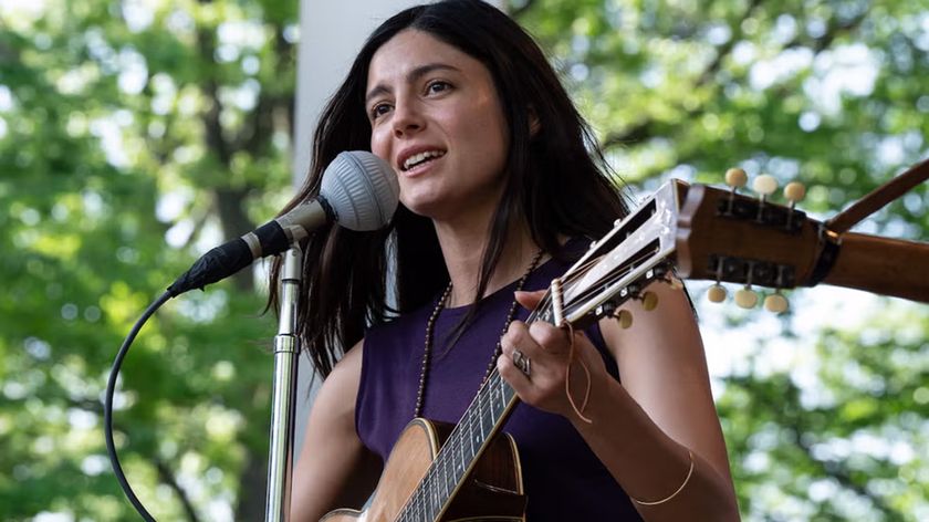 Monica Barbaro playing guitar in the role of Joan Baez