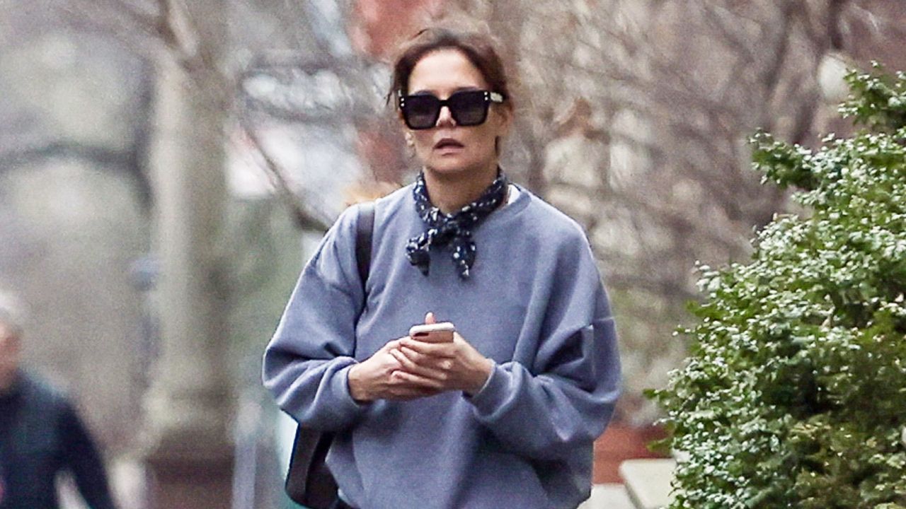 Katie Holmes walking in New York City wearing a sweatshirt and scarf with barrel-leg pants