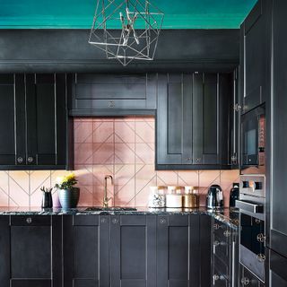 Black kitchen with green details and pink tiled splashback
