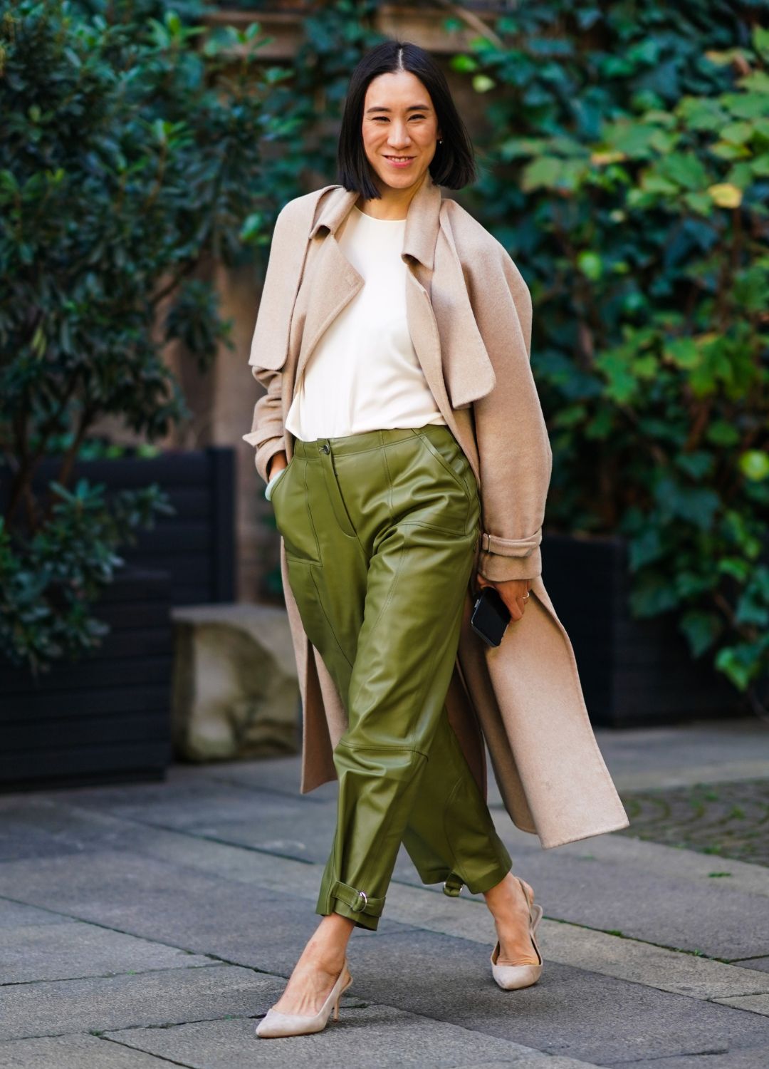 Eva Chen wears a beige long coat, a white t-shirt, green leather pants, pointy shoes, outside Koche x Pucci, during Milan Fashion Week Fall/Winter 2020-2021 on February 20, 2020 in Milan, Italy.