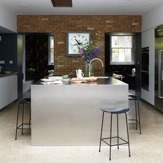 kitchen area with grey counter stools brick wall and white flooring