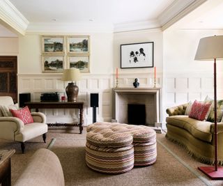 traditional living room with wainscoting, a green velvet fringed curved couch and a clover shape fabric covered ottoman