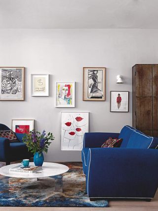 A white painted living room with artworks on the wall and a bold navy blue sofa
