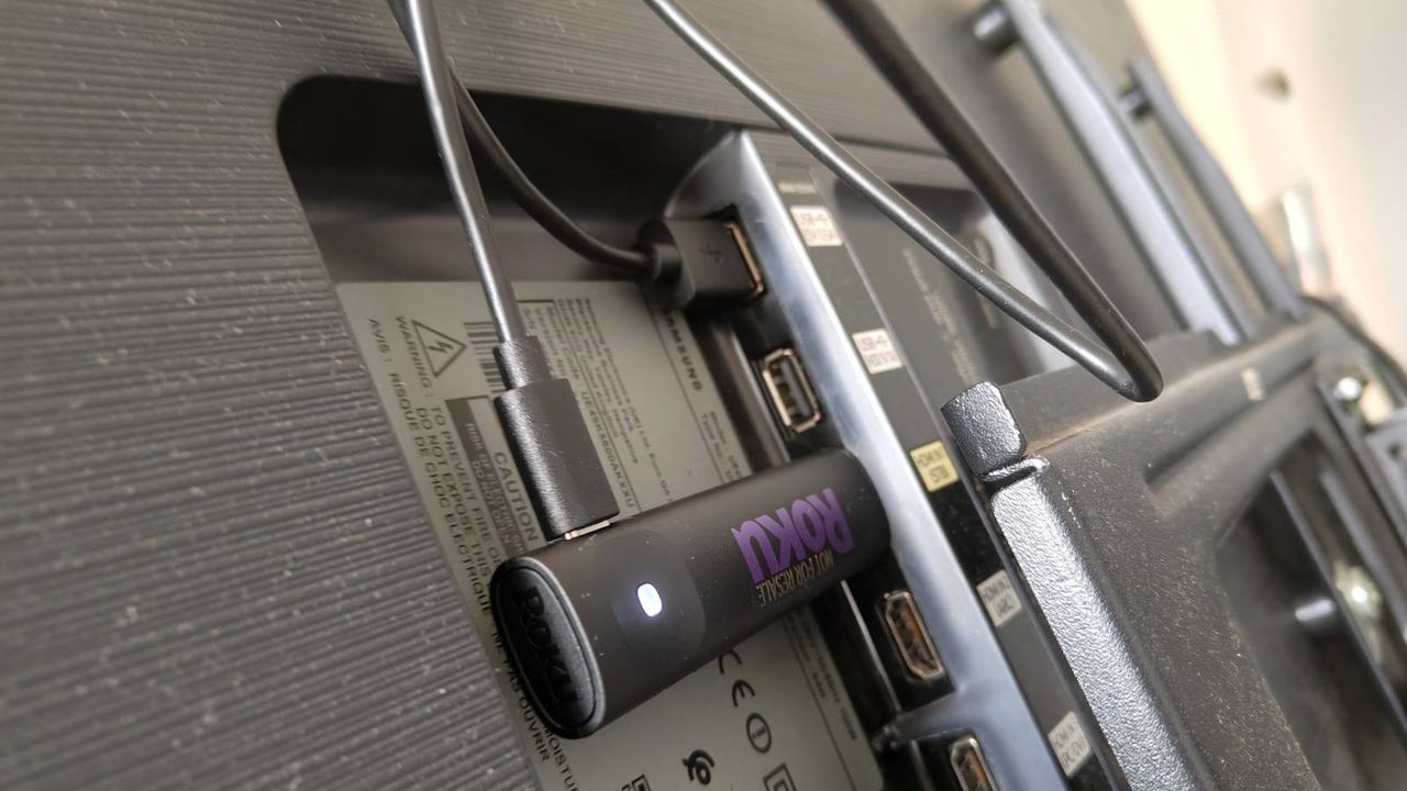 The Roku Streaming Stick fully plugged into the back of a TV.