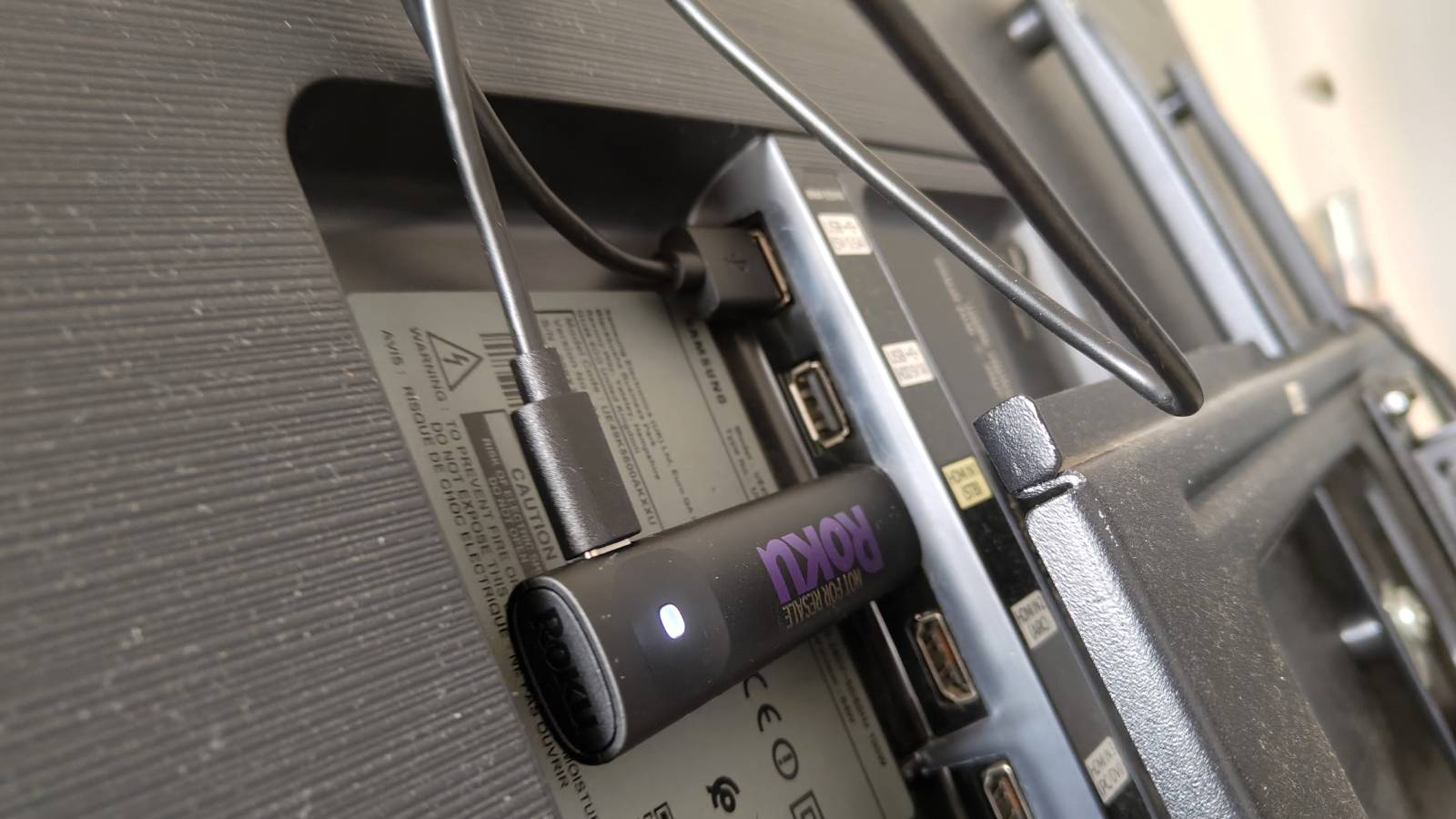 The Roku Streaming Stick fully plugged into the back of a TV.