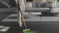 A woman using a Dyson cordless vacuum 