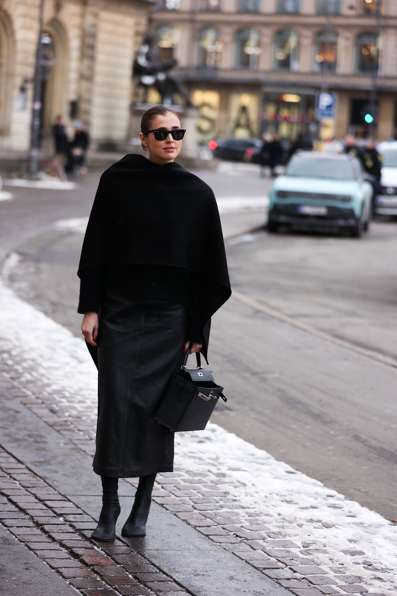 woman wearing black coat, black skirt, and boots