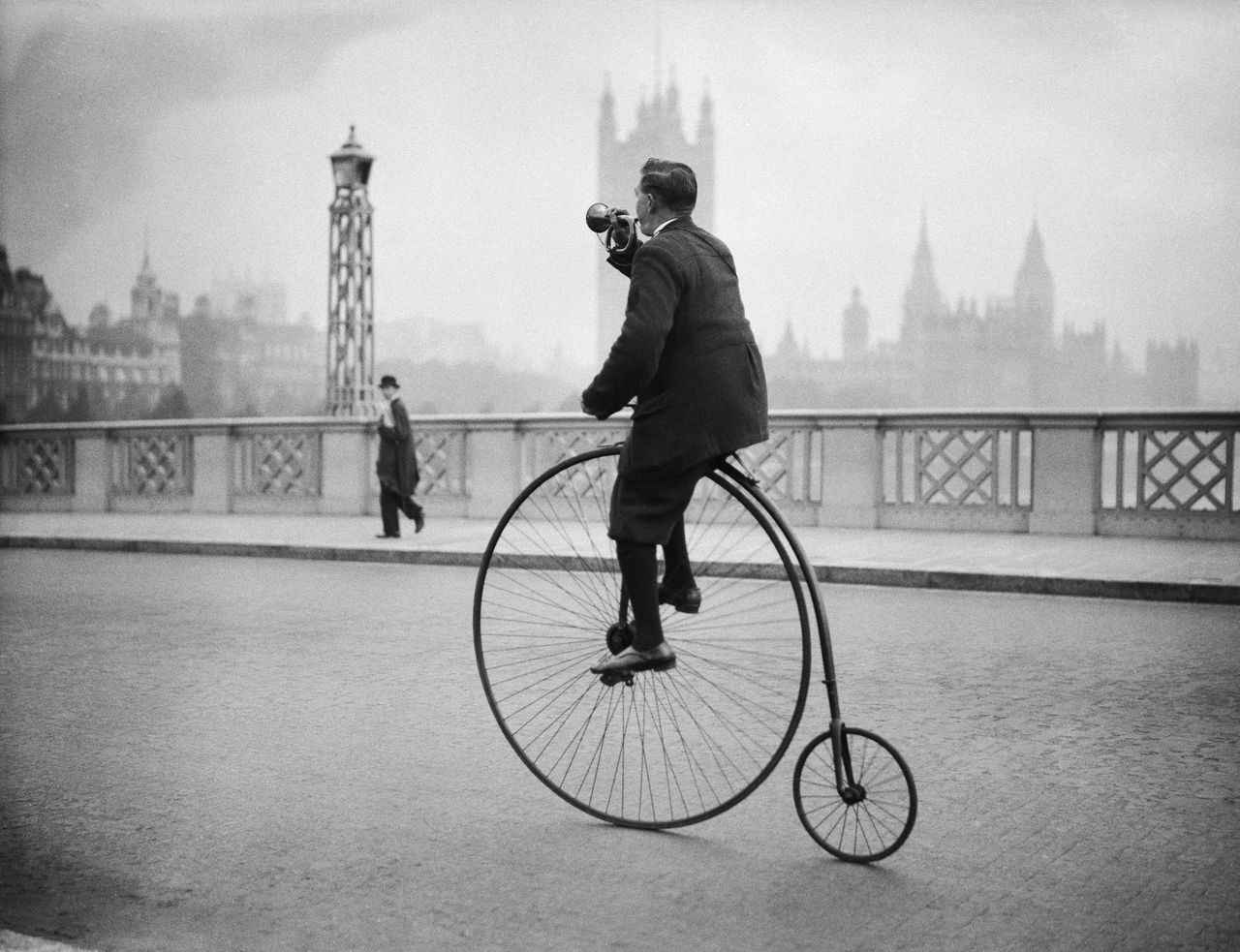 17th October 1932: Edwin Davey, riding a penny farthing bicycle over Lambeth bridge in London, and blowing a bugle to warn of his approach. (Photo by Fox Photos/Getty Images)