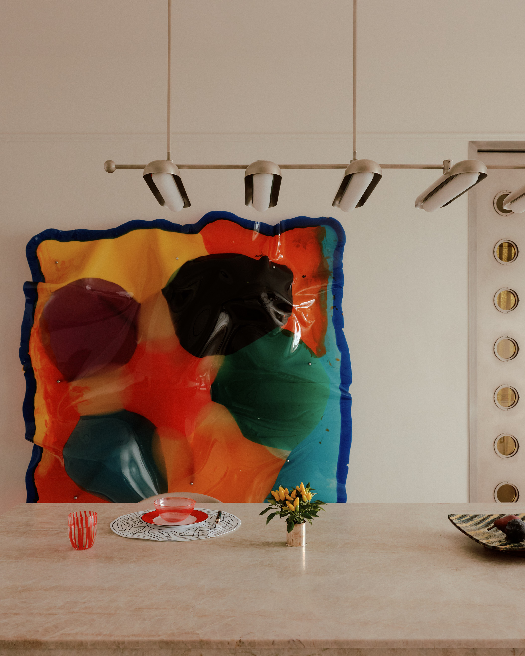 bold artwork on the wall in neutral kitchen with pendant light over the island bench and plates and cup styled on the counter