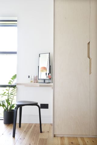 Plywood wall cupboard and built-in vanity desk with black stool
