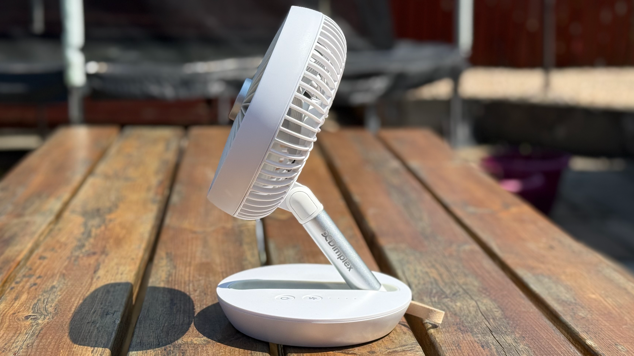 Side view of the Dimplex Rechargeable Cordless Desk Fan on a wooden bench table