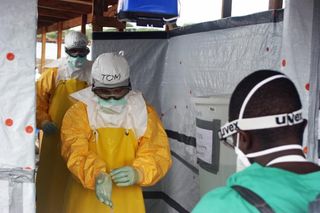 Staff members of Médecins Sans Frontières, or Doctors Without Borders, conduct a decontamination process on Dr. Tom Frieden, CDC Director, who is dressed in his personal protective equipment and is exiting an Ebola treatment unit in Monrovia, Liberia.